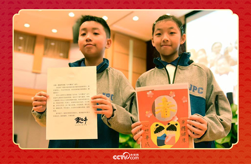 圖為香港“少年警訊”成員郭宏晞（左）展示習(xí)主席回信、羅顥凝（右）展示送給習(xí)主席的賀卡并合影。